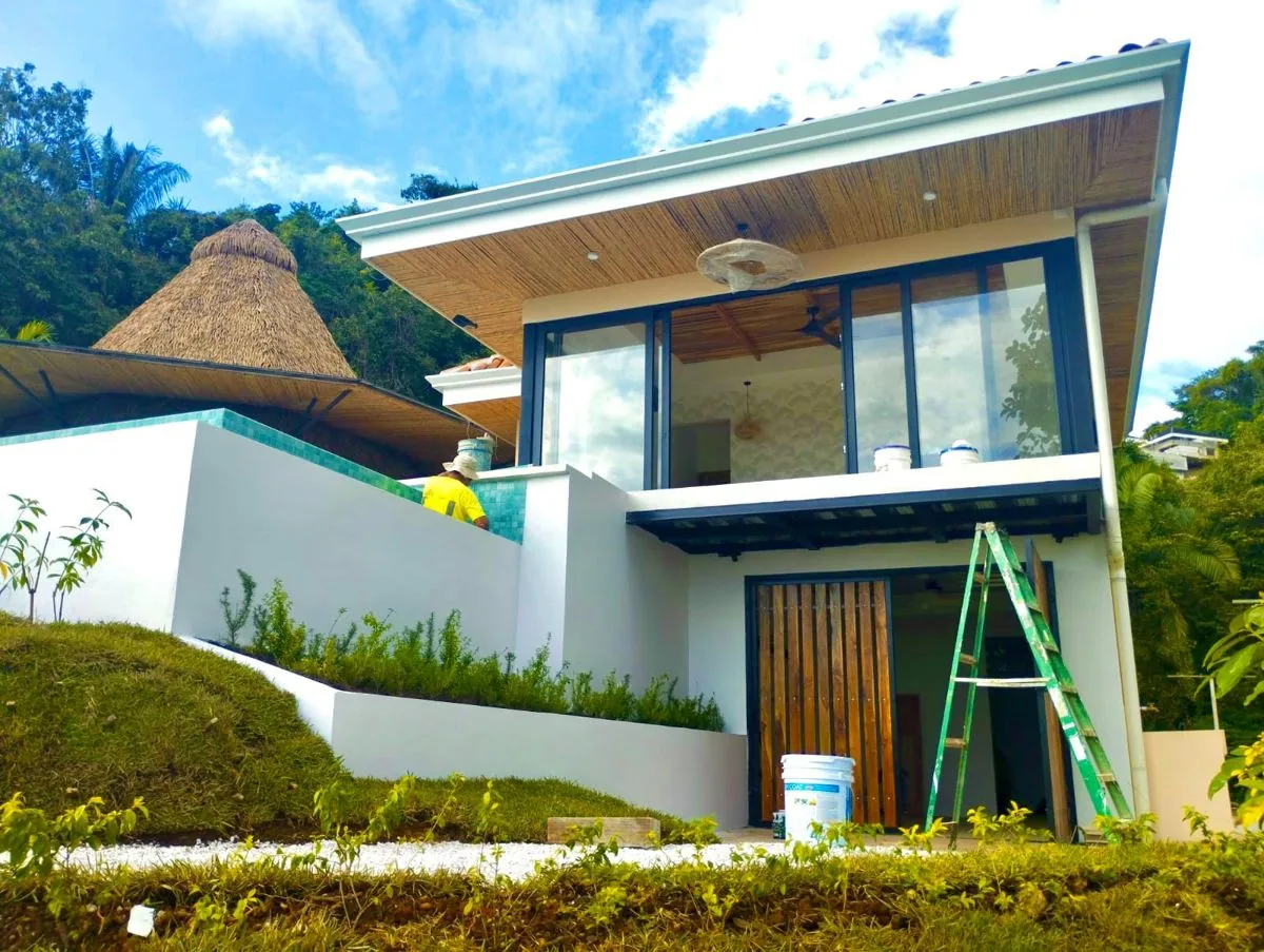 Villa Pochote, a white two-storey home with a palapa roof beside it