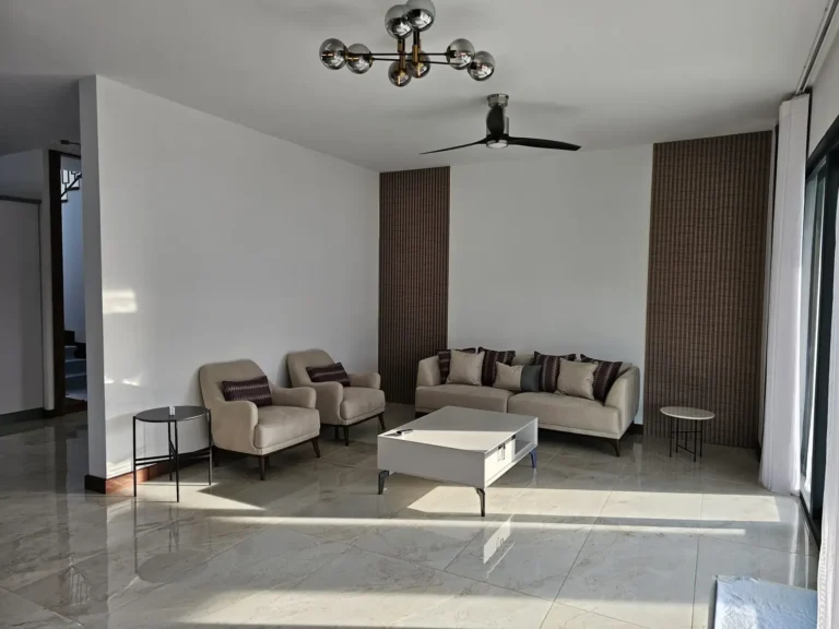 Furnished living room with cream sofas and a wood accent wall.