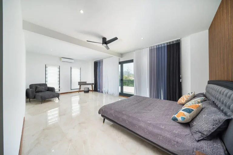 Primary bedroom with sheer curtains and large windows to the garden.