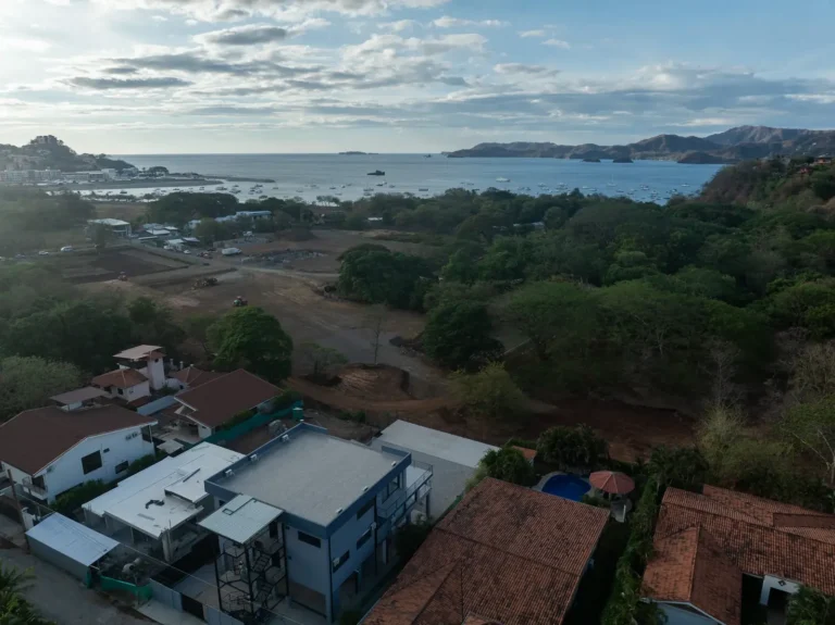 Casa Dos Hermanas seen from above with the green hills and Flamingo Bay stretching out behind it.