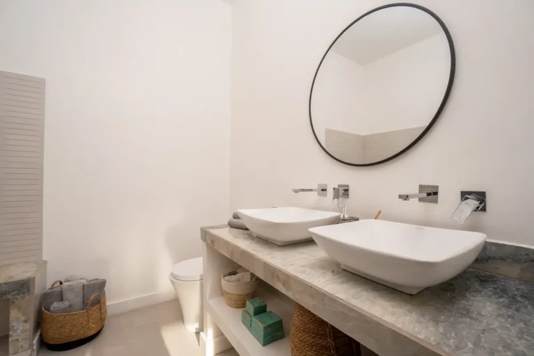 Bathroom with a stone double vanity, vessel sinks and woven storage baskets.