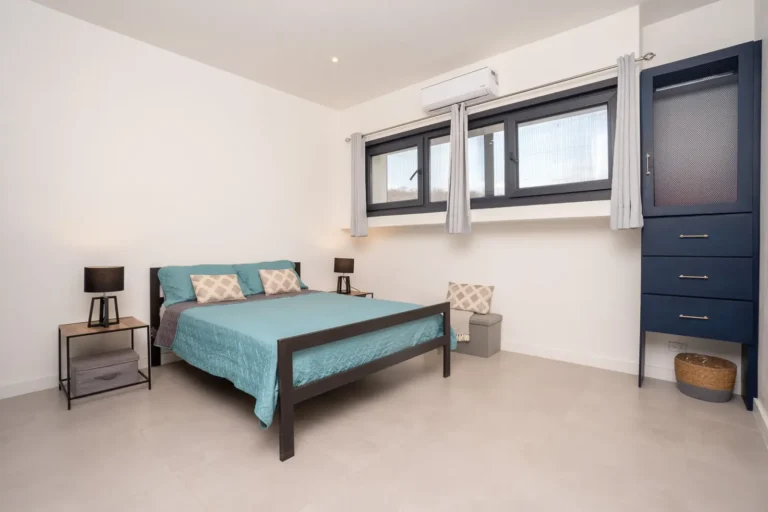 Guest bedroom with teal bedding, bedside lamps and blue curtains.