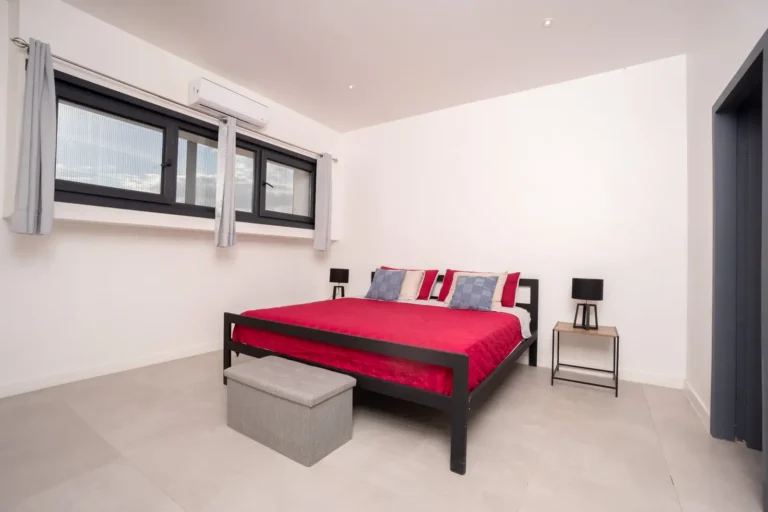 Bedroom with a king bed, red bedding and a band of clerestory windows.