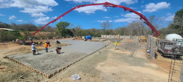 Concrete pump boom pouring the foundation slab while crews spread the concrete.