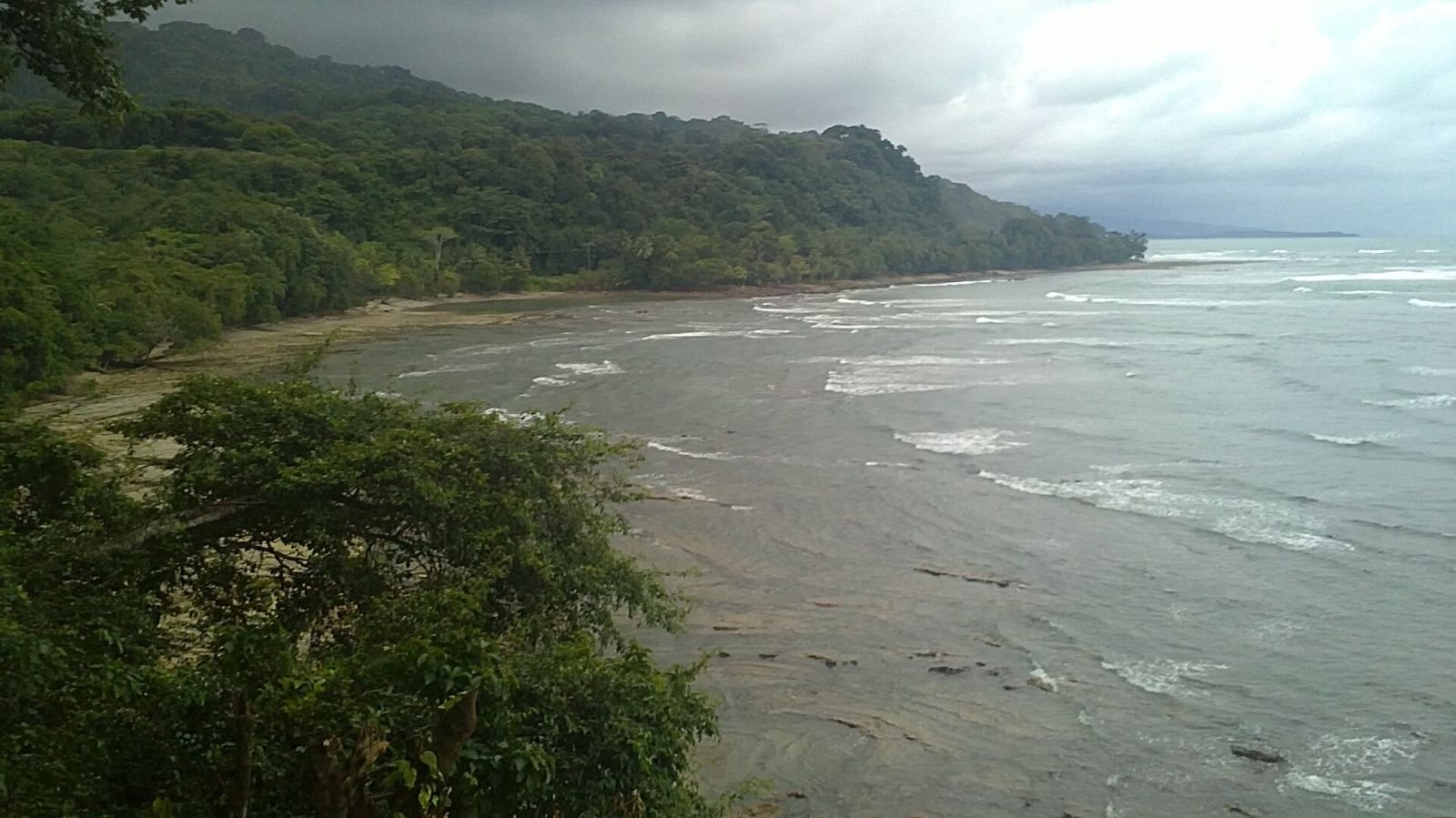 Forested headland and surf along the coast at Dominical, Costa Rica.