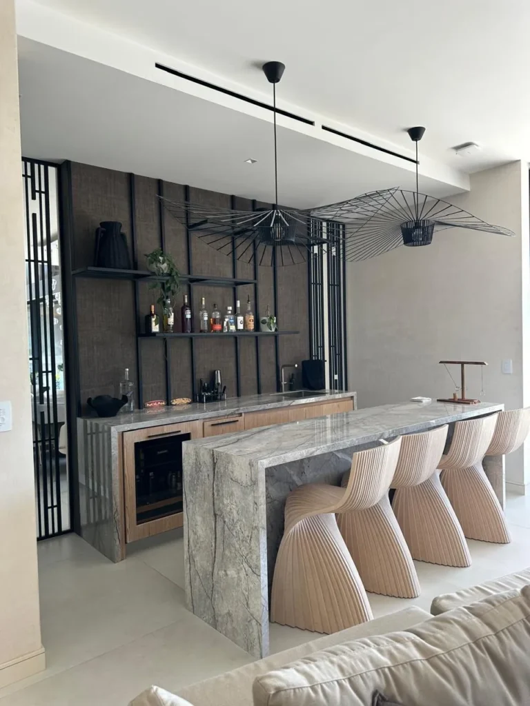 Home bar with stone counter and pendant lights in a renovated living area