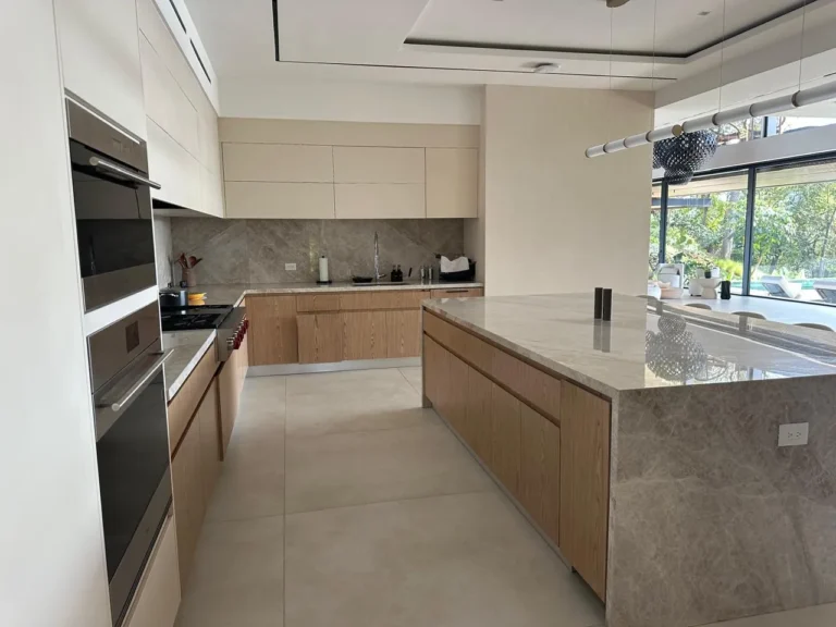 Kitchen renovation with built-in wall ovens, stone backsplash and long island