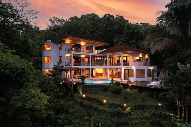 Multi-level rainforest villa in Manuel Antonio glowing at dusk among the trees.