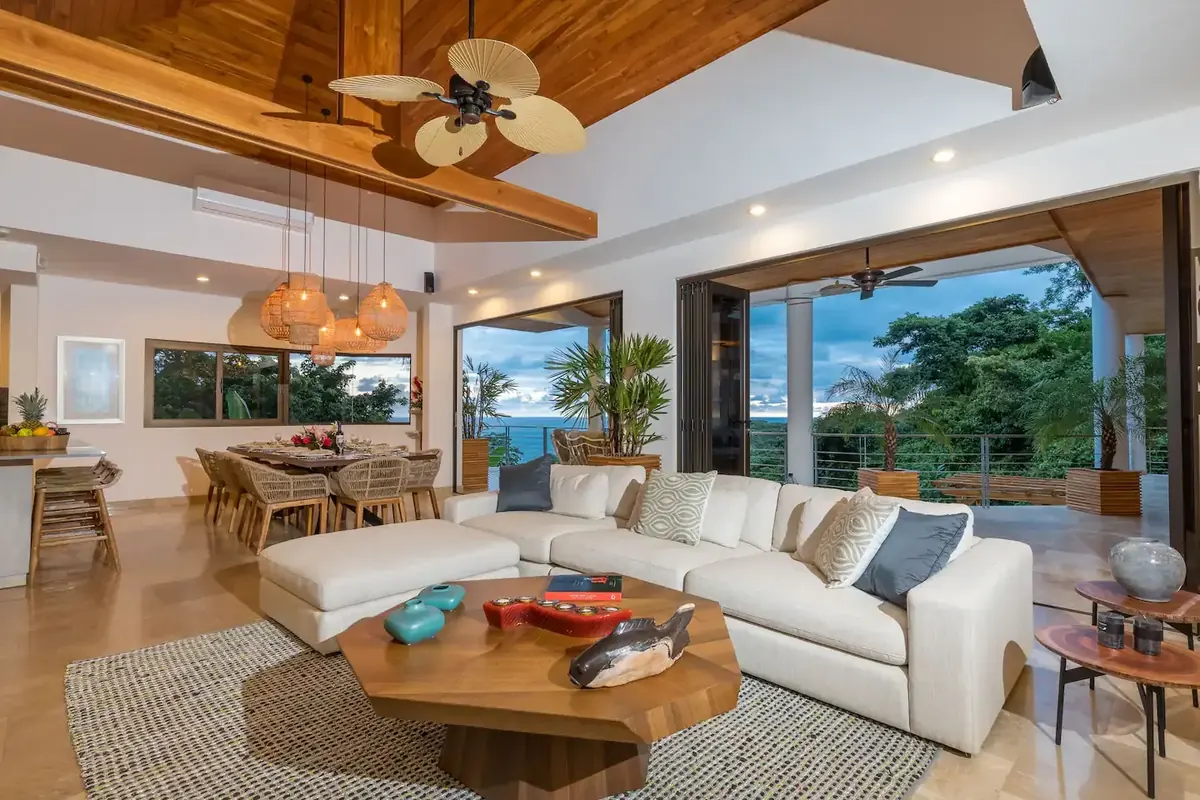 Great room of the Manuel Antonio rainforest villa with a white sectional and wood ceiling, open to the dining area