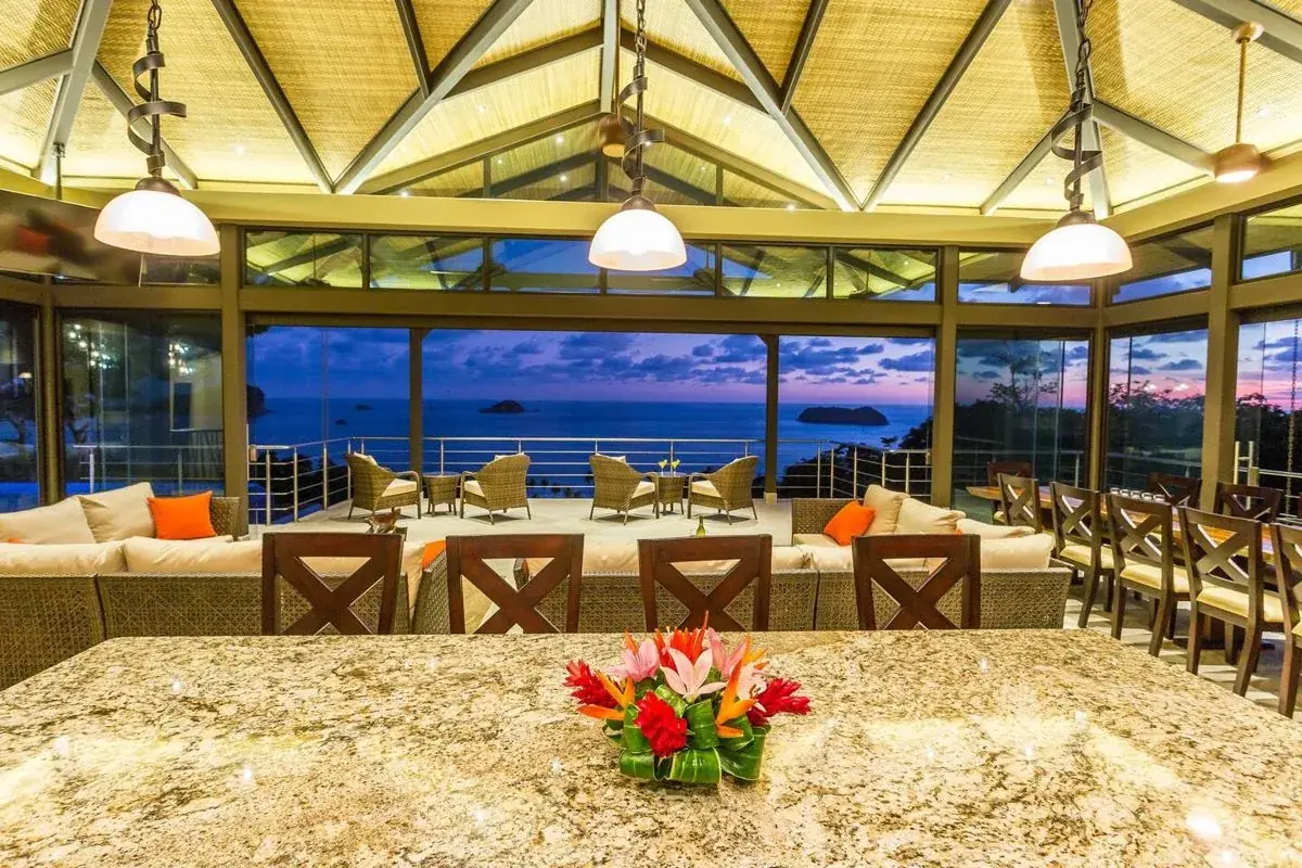 Great room of the Manuel Antonio villa with a stone island and ocean view at sunset