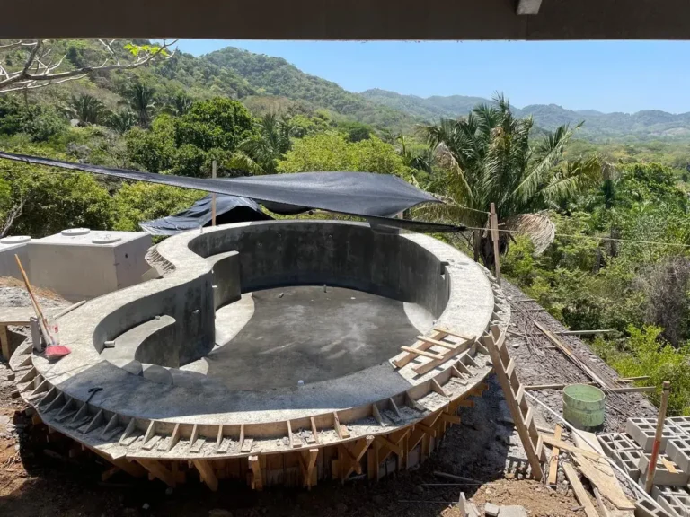 Curved pool walls in formwork on a hillside site above the forest.
