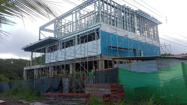 Three-storey light-gauge steel frame of Casa Dos Hermanas rising behind the site fence.