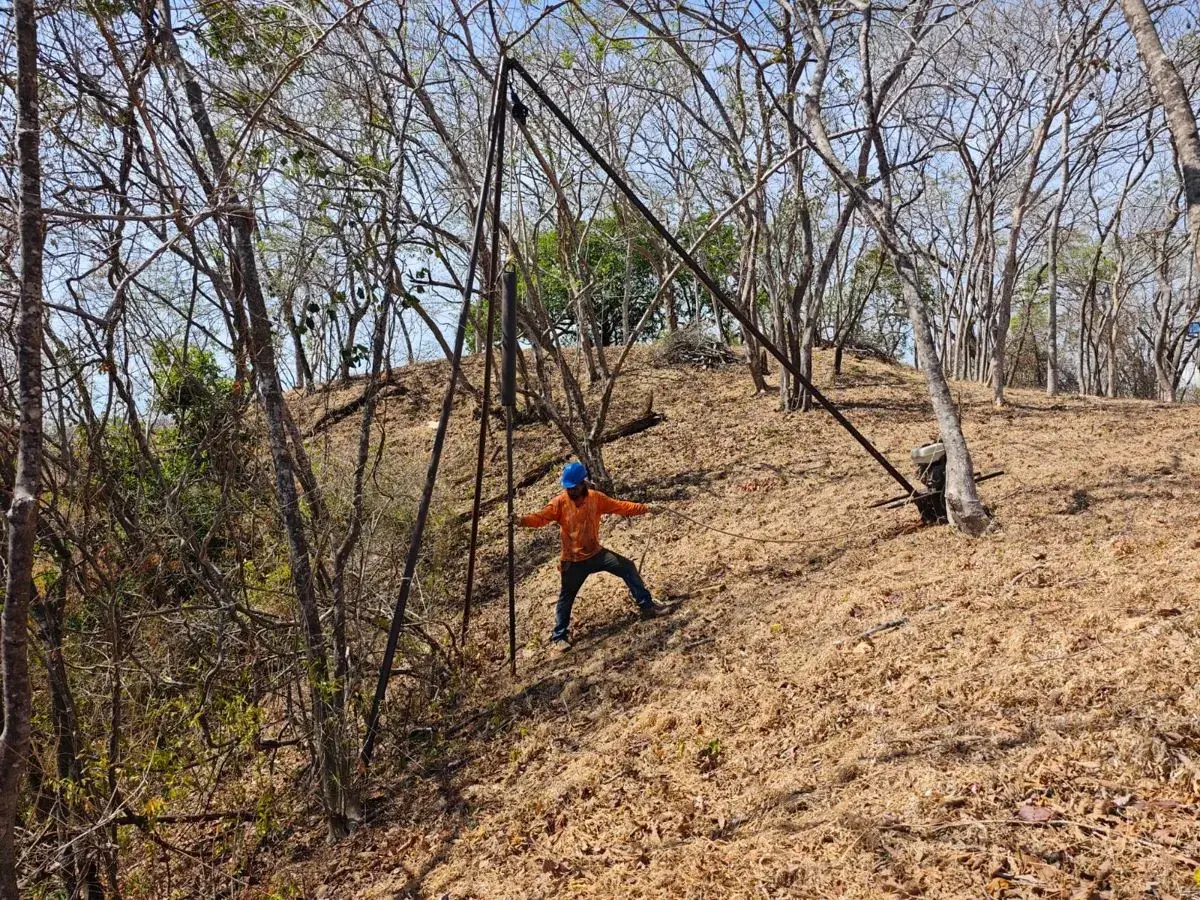 Surveyor measuring a dry-season hillside lot in Guanacaste before construction