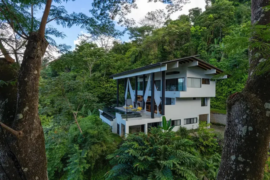 Modern hillside home in Uvita surrounded by tall rainforest trees.