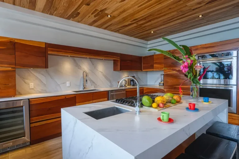 Kitchen with a white stone island, tropical-wood ceiling and fresh flowers.