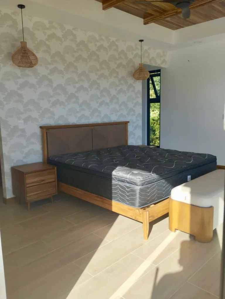 Guest bedroom with a wood bed and botanical wallpaper